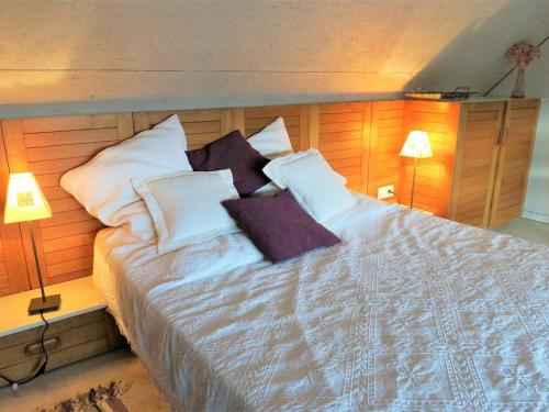 um quarto com uma cama grande com lençóis brancos e almofadas em Maison Trégastel, 1 pièce, 2 personnes - FR-1-368-211 em Trégastel