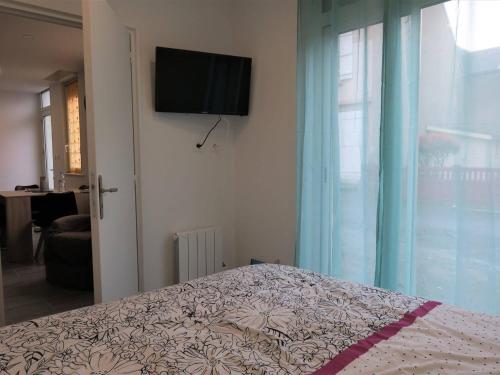 ein Schlafzimmer mit einem Bett und einem TV an der Wand in der Unterkunft Appartement rénové 3* avec WIFI, centre-ville Perros-Guirec, proche plages et commerces - FR-1-368-263 in Perros-Guirec
