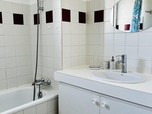 une salle de bain avec un lavabo, une baignoire et un miroir dans l'établissement Appartement T2 Confortable avec Véranda et Parking - Proche Centre - Cambo-les-Bains - FR-1-495-108, à Cambo-les-Bains