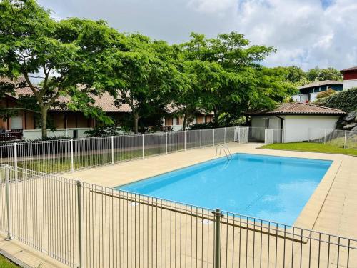 a large blue swimming pool next to a fence at Appartement T2 avec Piscine, Proche Thermes, Parking Souterrain et Terrasse - Cambo-les-Bains - FR-1-495-72 in Cambo-les-Bains
