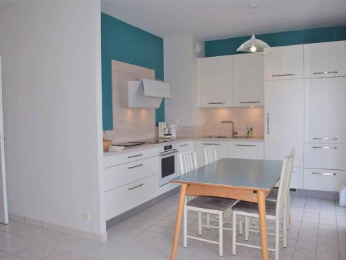 une cuisine avec des armoires blanches et une table et des chaises dans l'établissement Appartement 3* rénové avec terrasse et parking, au centre de Perros-Guirec, 5 personnes - FR-1-368-166, à Perros-Guirec