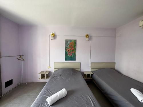 a bedroom with two beds and a painting on the wall at Ginger Sihanoukville in Sihanoukville