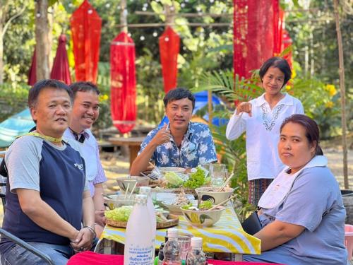 een groep mensen die aan een tafel zitten met eten bij กิ่วลม - ชมลคอร Kiwlom - Chomlakorn, Lampang, TH in Lampang
