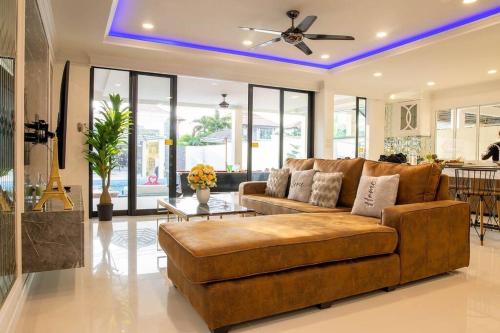 a living room with a brown couch and a ceiling fan at Exquisite Pool Villa J - Pattaya Pool Villa in Pattaya South