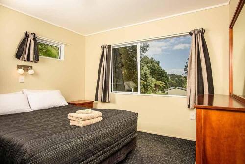 a bedroom with a bed and a large window at Tasman Holiday Parks - Ohiwa in Opotiki