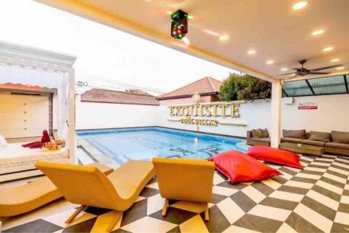 a swimming pool in a room with chairs and a couch at Exquisite Pool Villa K - Pattaya 6BD Pool Villa in Pattaya South