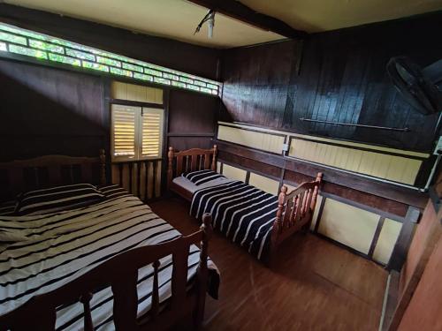 Duas camas num quarto com paredes de madeira em Port Mancing Fishing Village em Kampong Ulu Kalong