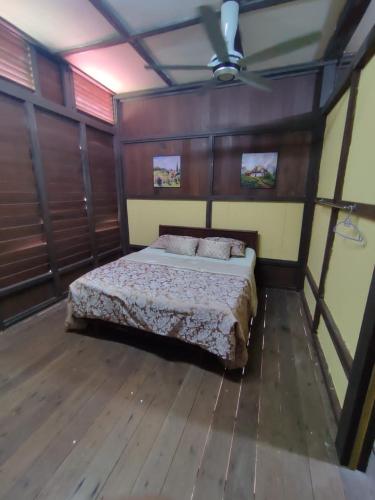 um quarto com uma cama num quarto com pisos em madeira em Port Mancing Fishing Village em Kampong Ulu Kalong