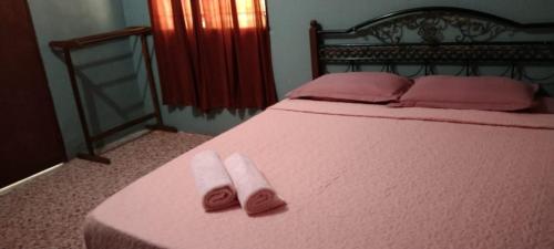 Una cama con sábanas rosas y toallas rosas. en Durian Chalet en Kuala Tahan