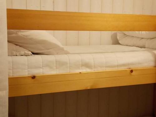ein Etagenbett aus Holz mit weißer Bettwäsche und Kissen in der Unterkunft Studio Saint-Jean-d'Aulps, 1 pièce, 4 personnes - FR-1-573-110 in Saint-Jean-dʼAulps
