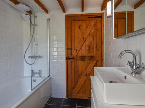 a bathroom with a wooden door and a tub and a sink at Hook Cottage in Looe
