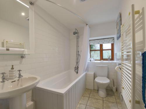 a bathroom with a tub and a toilet and a sink at Lily Cottage in Looe