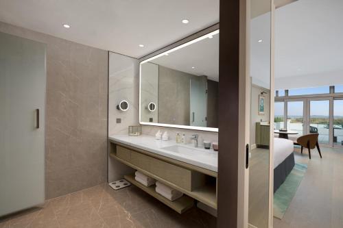 a bathroom with a sink and a bed and a mirror at Xiamen International Seaside Hotel -Hotel corridor leads to the stone exhibition hall in Xiamen
