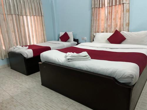 two beds in a room with red and white sheets at The North Face Inn in Pokhara