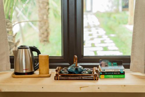 een tafel met een koffiezetapparaat, boeken en een raam bij 6Nature Bavi Retreat in Hanoi