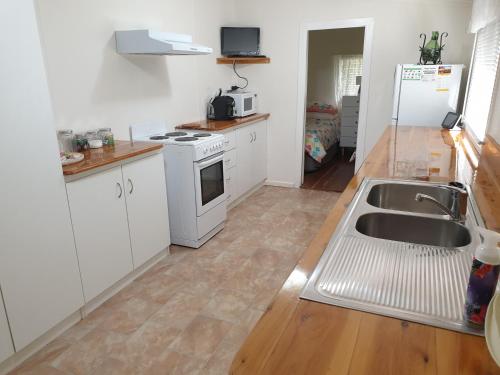 a kitchen with white cabinets and a sink at Browncoat Cottage Mudgee in Mudgee
