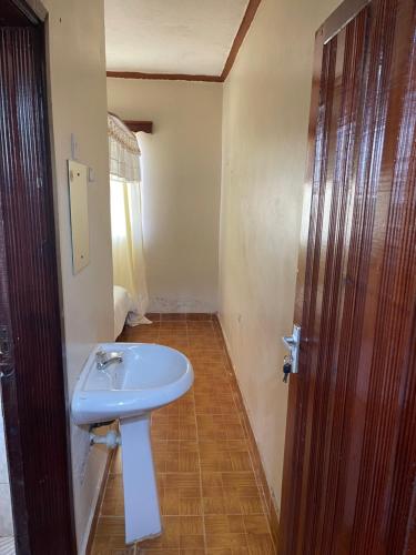 Łazienka z białą umywalką i drewnianymi drzwiami w obiekcie Easy Sleep Guesthouse w Kitale