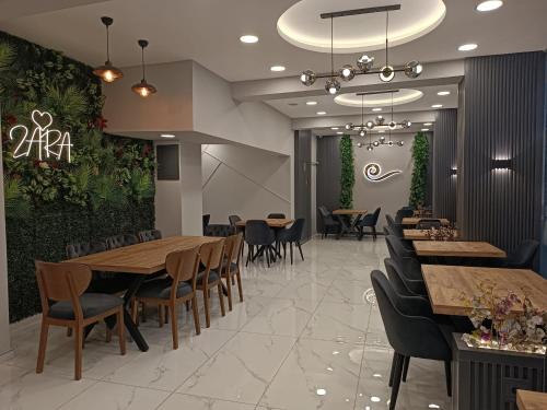 um restaurante com mesas de madeira, cadeiras e plantas em Gulistan Hotel em Zara