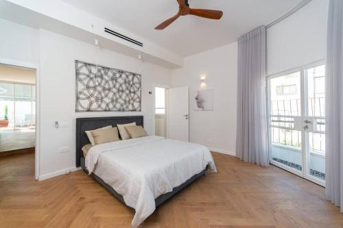 a white bedroom with a bed and a ceiling fan at Decoreted 2 bed. Penthouse with a sun terrace in Tel Aviv
