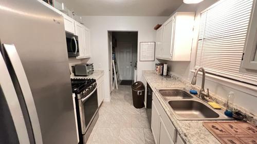 cocina con armarios blancos y nevera de acero inoxidable en Amazing Bedroom Suite/Private Bathroom, en Houston