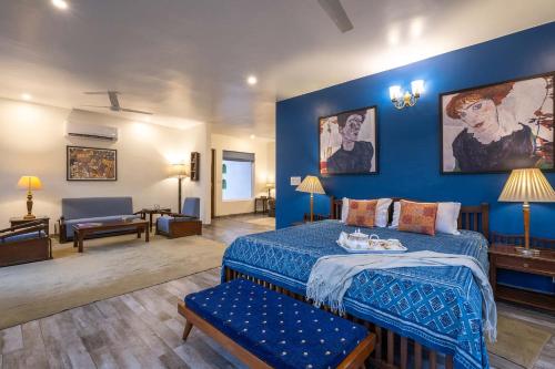 a blue bedroom with a bed and a couch at StayVista at The Hideout with private outdoor pool in Kurukshetra