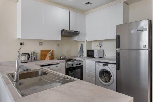 a kitchen with a stainless steel refrigerator and a dishwasher at Bright and spacious apartment in DAMAC HILLS in Dubai