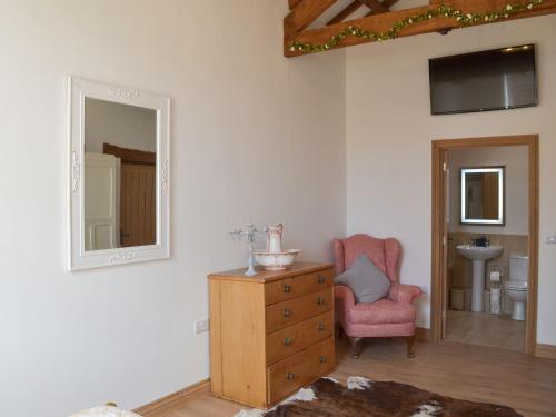 a room with a dresser and a chair and a mirror at Court Barn in Buckerell