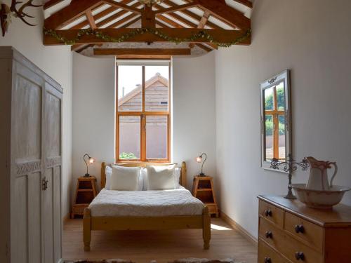 a bedroom with a bed with two pillows and a window at Court Barn in Buckerell