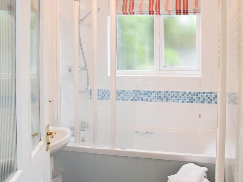 La salle de bains blanche est pourvue d'une douche et d'un lavabo. dans l'établissement Lavenham Red Brick Cottage, à Lavenham