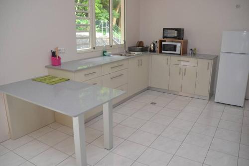 Il comprend une cuisine équipée d'une table blanche et d'un réfrigérateur. dans l'établissement Papeete appartement F2, à Papeete