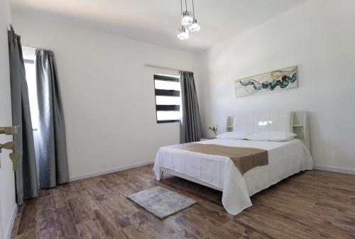 a white bedroom with a bed and a window at villa de la lumiere in Trou aux Biches