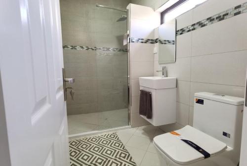 a white bathroom with a shower and a toilet at villa de la lumiere in Trou aux Biches