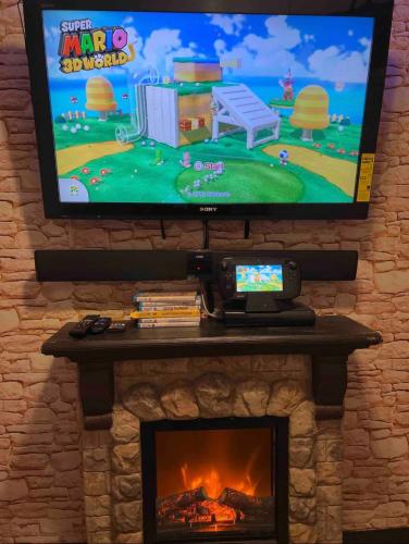 a tv above a fireplace with a video game on it at Nice Cozy Room By Empire City Casino And Cross County Mall in Yonkers