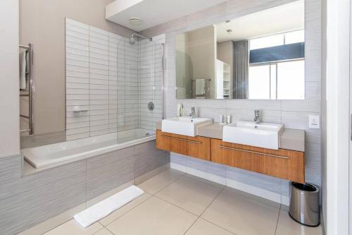 La salle de bains est pourvue de 2 lavabos, d'une baignoire et d'un miroir. dans l'établissement Luxury 2 bed apart 515 Harbour Bridge, Dockrail Road, Foreshore, Cape Town, 8001,, au Cap