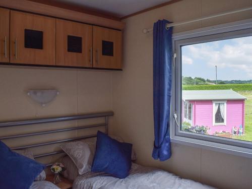 um quarto com uma janela, uma cama e uma casa cor-de-rosa em Tranquillity Lodge em Annbank