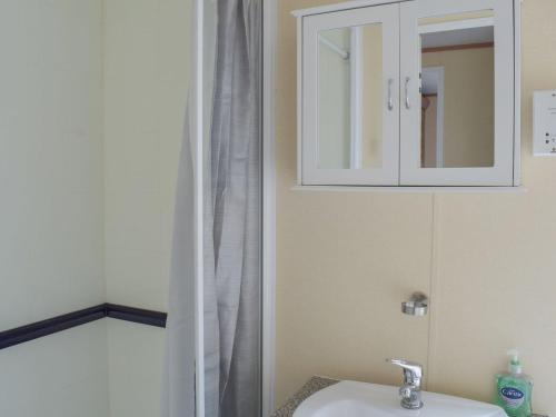 uma casa de banho com um lavatório e um armário de medicamentos em Tranquillity Lodge em Annbank