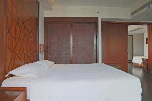 a bedroom with a large white bed with wood paneling at Mangrove Tree Resort World Sanya Bay-Kapok in Sanya