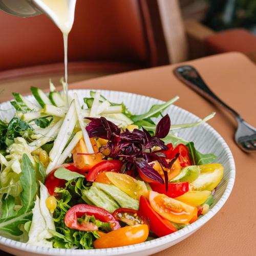 a plate of salad with dressing being poured on it at Royal Tulip Hotel & Casino, Tbilisi in Tbilisi City