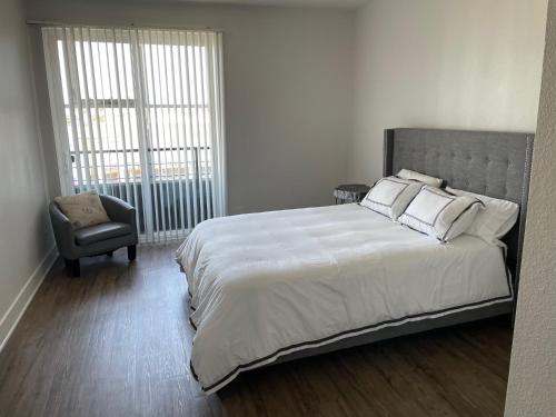 a bedroom with a large bed and a chair at Villa Marina - Modern & Immaculate, Spacious, Gated Condo with Fireplace Pool, Gym, 2 Master Bedrooms in Los Angeles