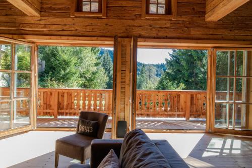 a living room with large windows and a couch at Luxury old wood mountain chalet in a sunny secluded location with gym, sauna & whirlpool in Scheffau am Wilden Kaiser