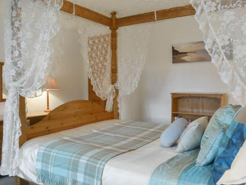 - une chambre avec un lit en bois et des oreillers bleus dans l'établissement Grannys Cottage, à Lostwithiel
