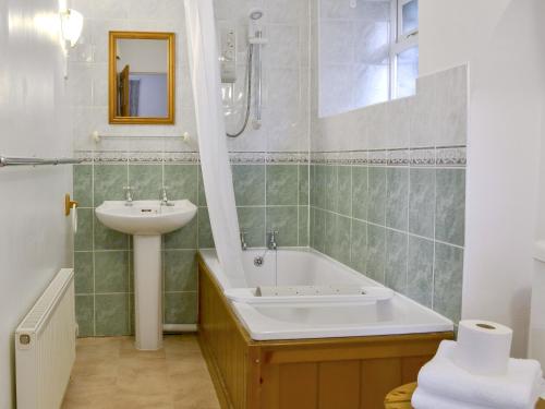La salle de bains est pourvue d'un lavabo et d'une baignoire. dans l'établissement Grannys Cottage, à Lostwithiel