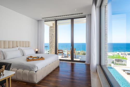 a bedroom with a bed and a view of the ocean at Cap St Georges Villas in Peyia