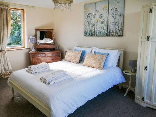 Un dormitorio con una cama blanca con toallas. en Broomhouse Lodge, en Edrom