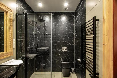a bathroom with a shower with black marble at Chochołowskie Zacisze przy Termach - Apartamenty i Pokoje in Chochołów