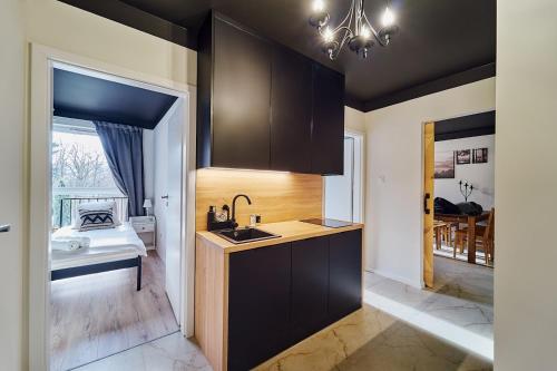 a kitchen with black cabinets and a sink and a bedroom at LAGUNA Villa Fonte 10 in Polanica-Zdrój