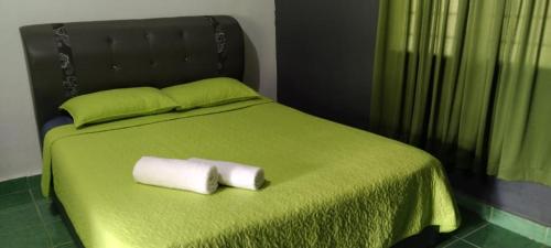 Una cama verde con dos toallas enrolladas. en Durian Chalet, en Kuala Tahan