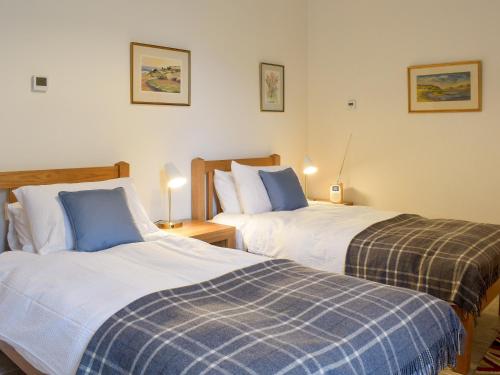 dos camas sentadas una al lado de la otra en un dormitorio en Tweedford Cottage-uk41063 en Drummelzier