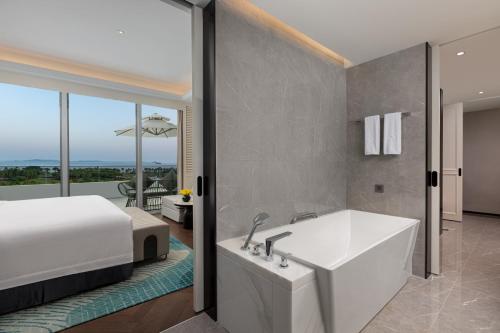 a bedroom with a tub and a bed and a view at Xiamen International Seaside Hotel -Hotel corridor leads to the stone exhibition hall in Xiamen