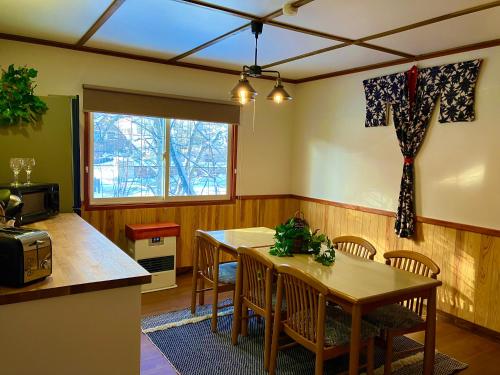 a dining room with a table and chairs and a window at Lodge Blue Mount Hakuba in Hakuba